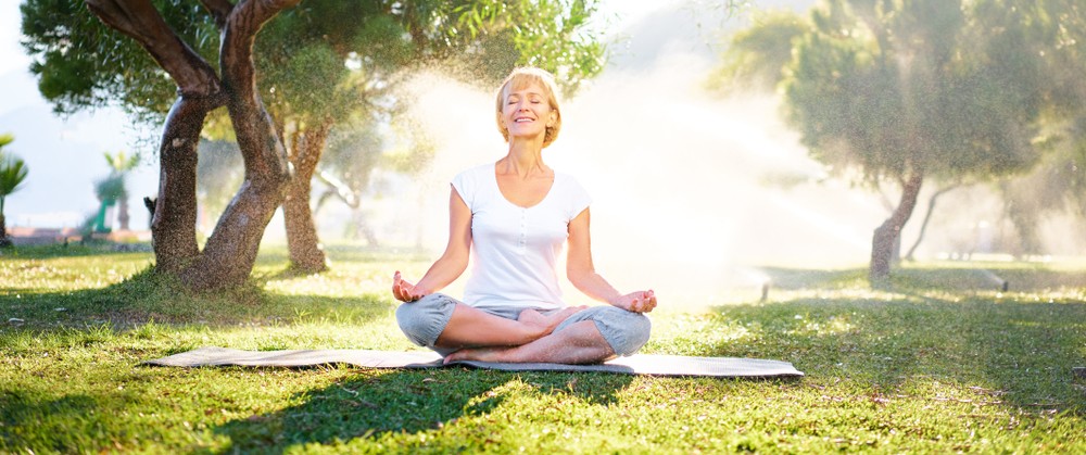 senior woman meditating at a park