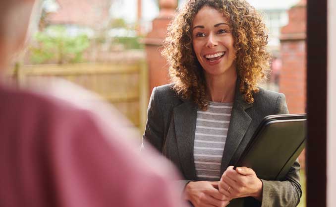 A woman is at the door of the house of a senior for in home care