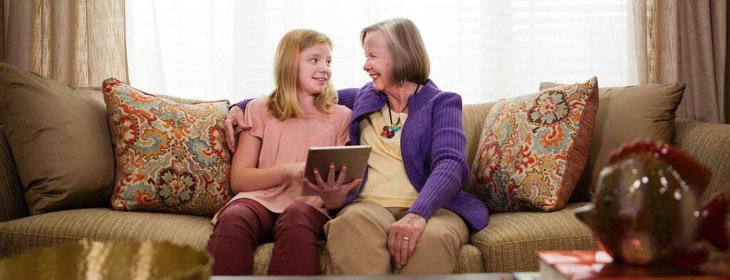 Granddaughter and her grandma sitting on a couh looking a memory book