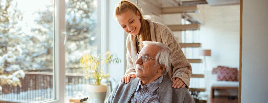 senior man with adult daughter looking out a window