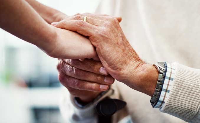 Elderly person holds hands with a younger person
