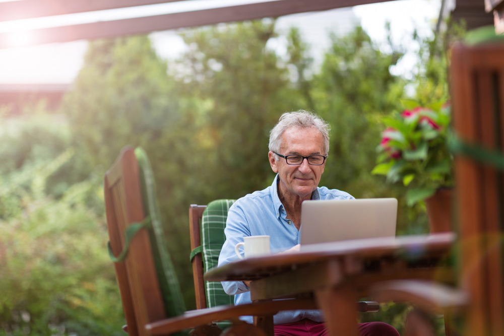 Senior man working on laptop Senior man working on laptop in the garden