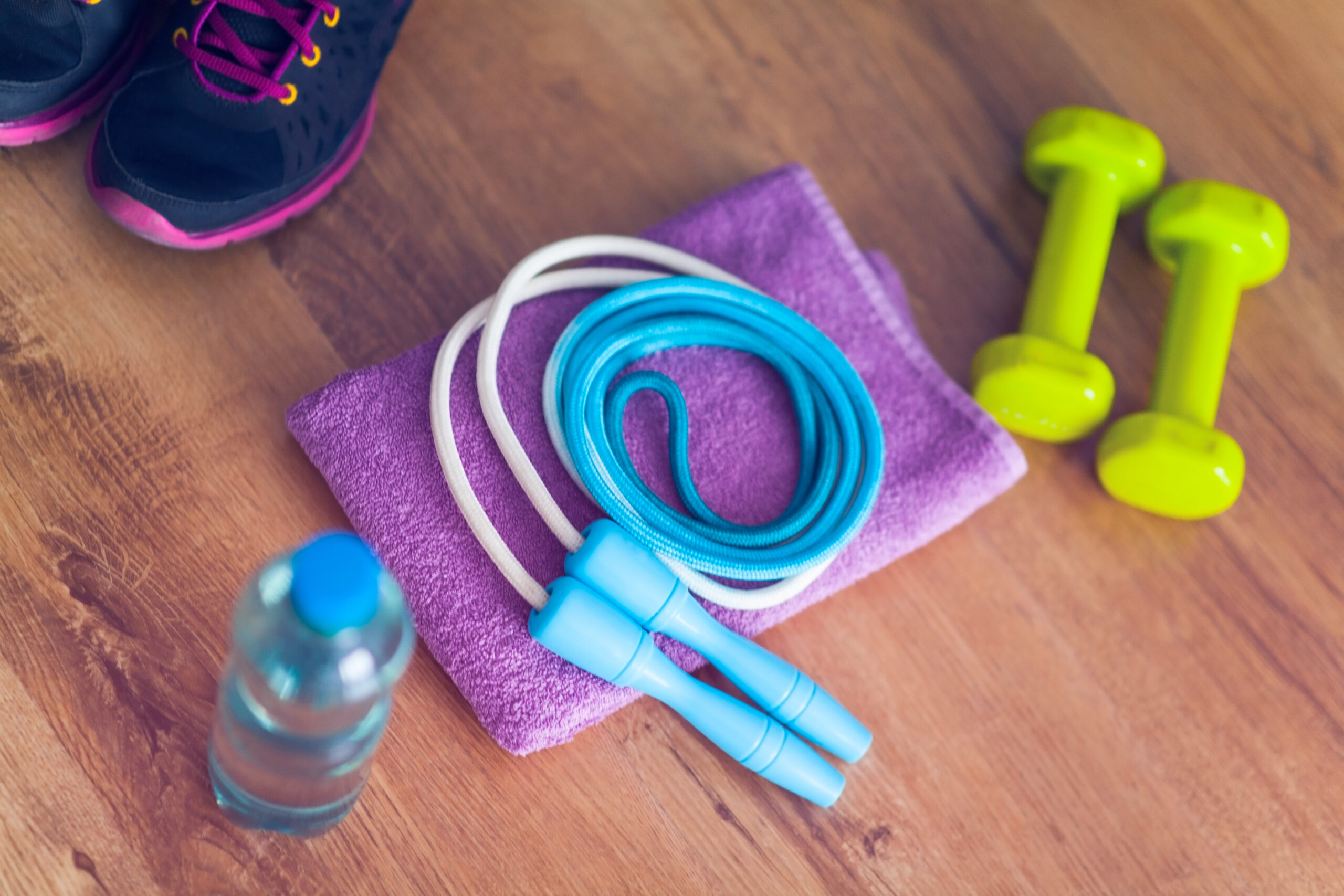fitness equipment, including dumbbells, jump rope, tennis shows, towel and a bottle of water
