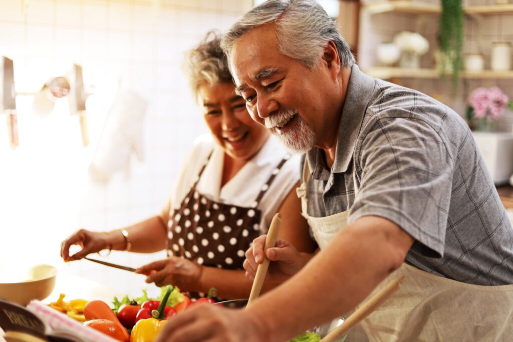 Happiness senior elderly couple having fun in kitchen with healthy food for working from home. 