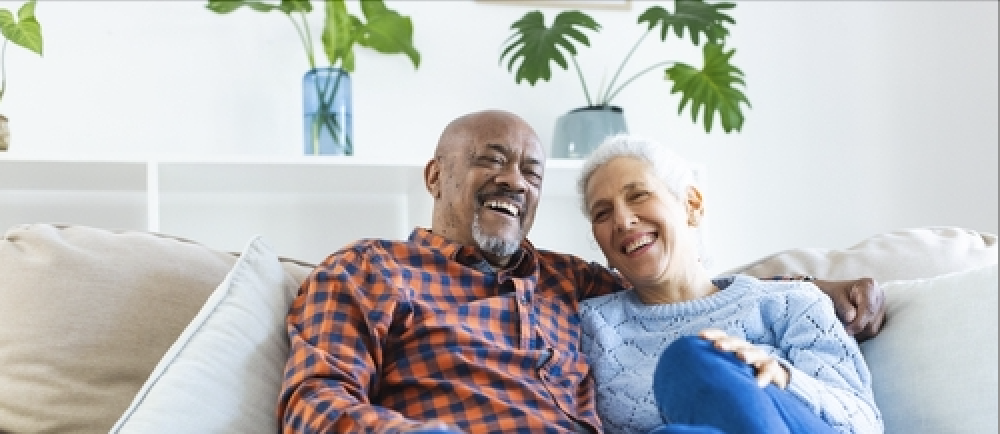 senior couple sitting on couch laughing