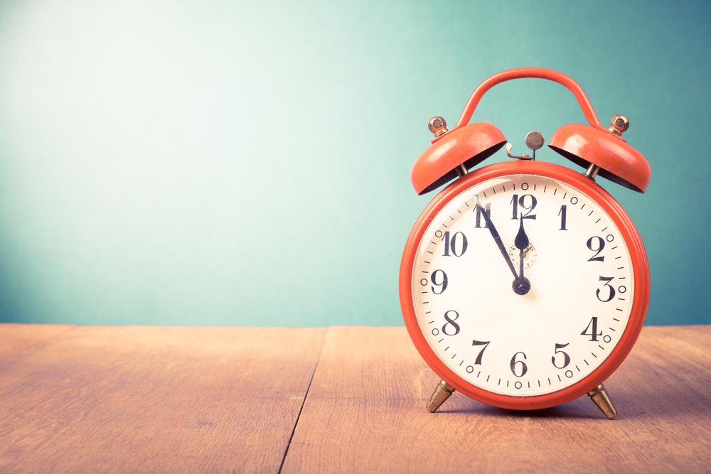 Retro,Alarm,Clock,With,Five,Minutes,To,Twelve,O’clock.,Old red alarm clock on a wooden desk