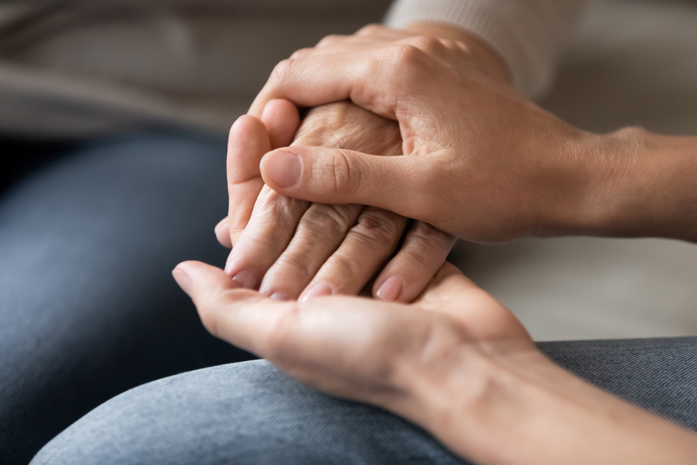 close up of young woman holding older woman's hand