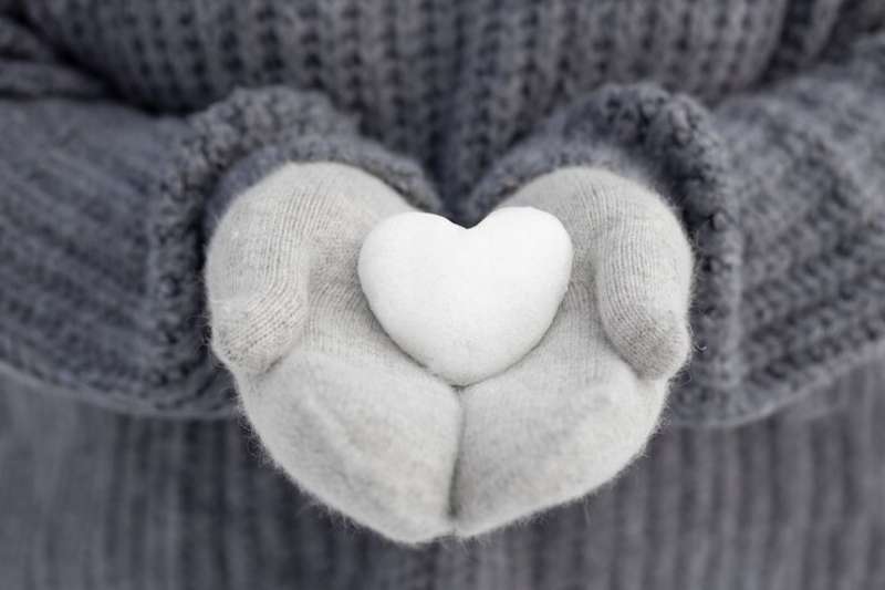 close-up-hands-holding-snow-heart hands holding a snow heart, wearing gloves
