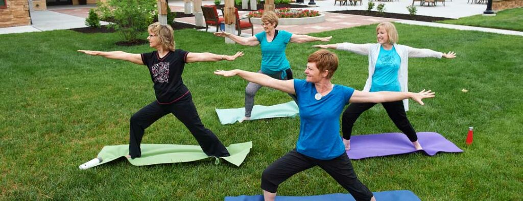 Four women gracefully practicing yoga in a community courtyard, promoting health, well-being and vibrant community living at John Knox Village.