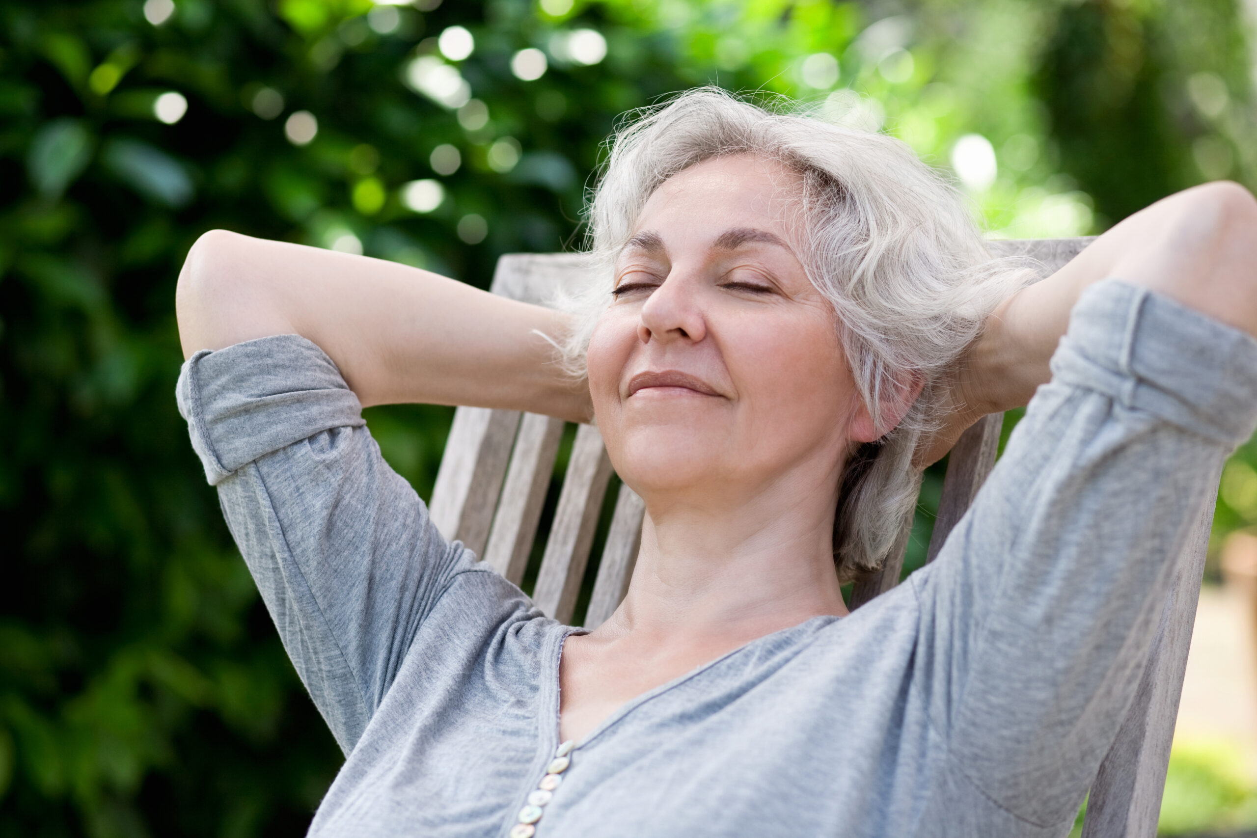 senior woman lounging outdoors with arms above head