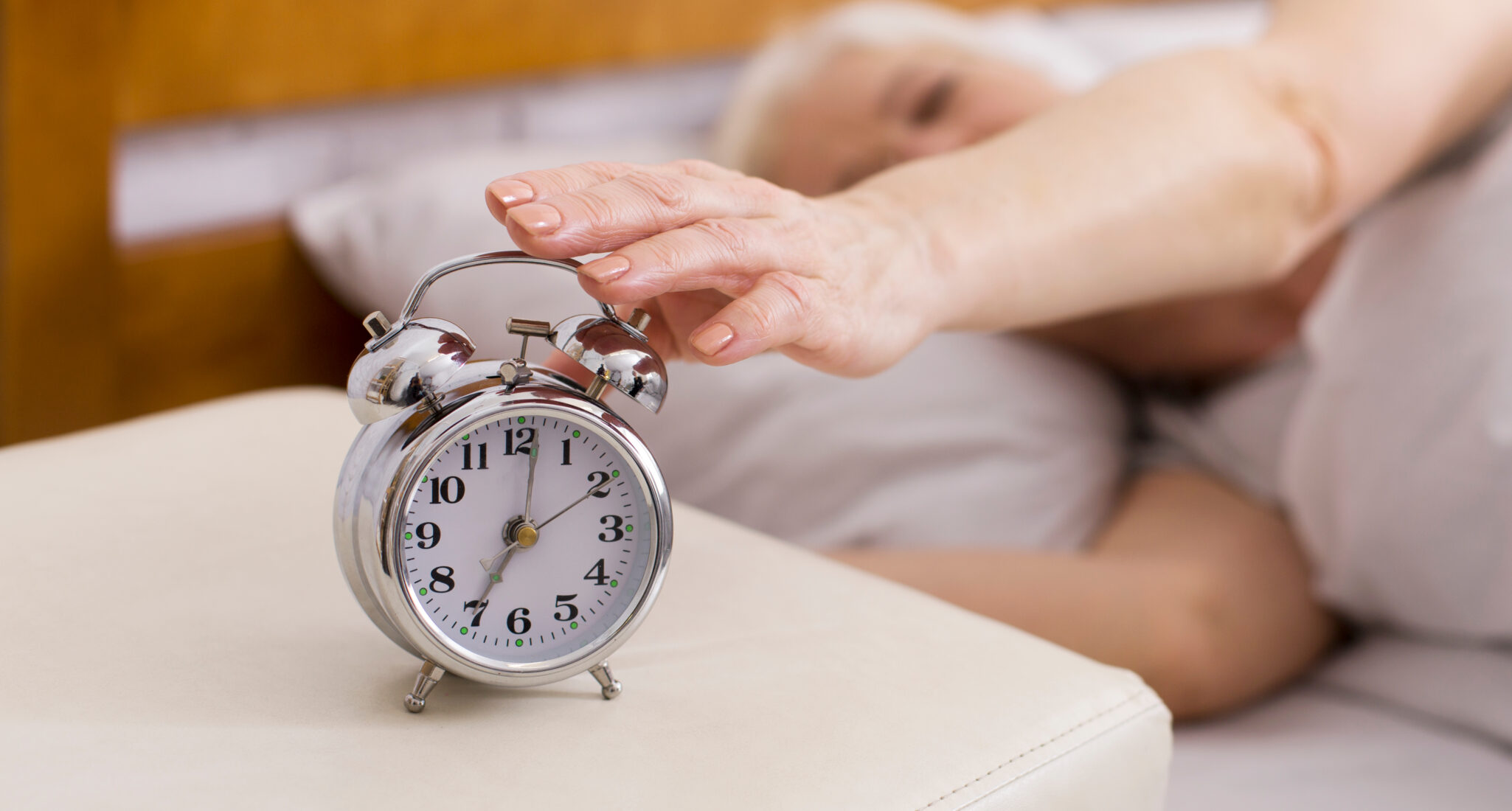 Wake,Up,Call.,Senior,Woman,Turning,Of,Alarm,Clock,,Lying Older woman sleeping and turning off alarm